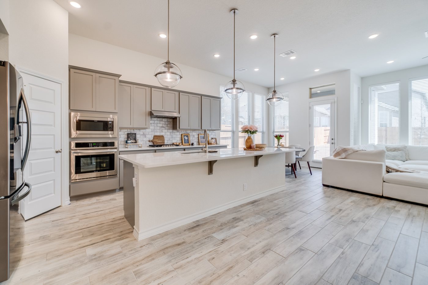 Finished open plan kitchen with a quartz island, gray shaker cabinets, and pendant lighting